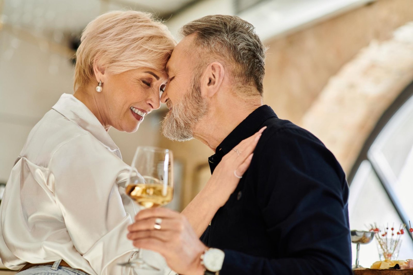 Moget par som ler nära varandra och delar ett glas vin