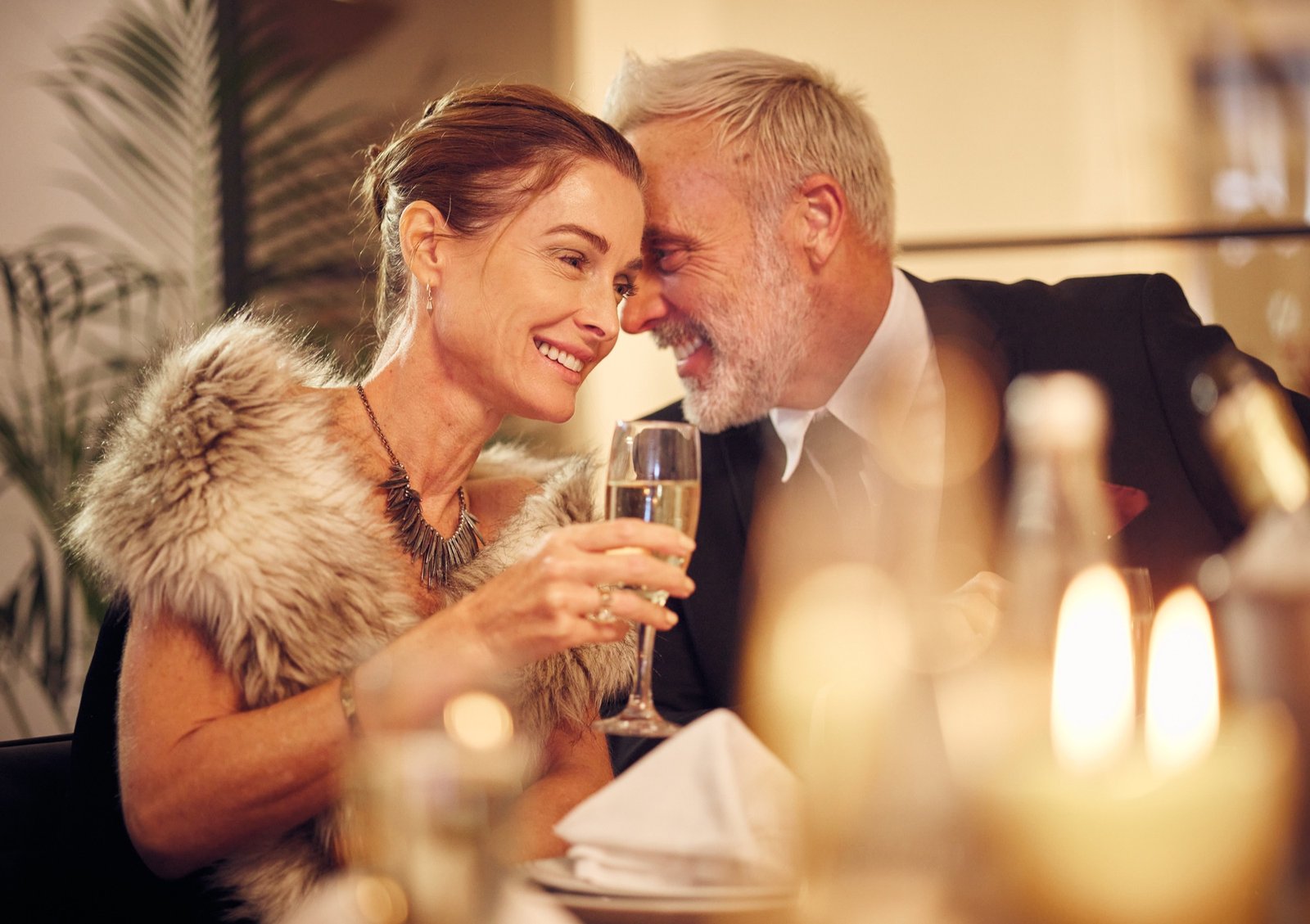 Moget par som ler mot varandra under en romantisk middag med champagne