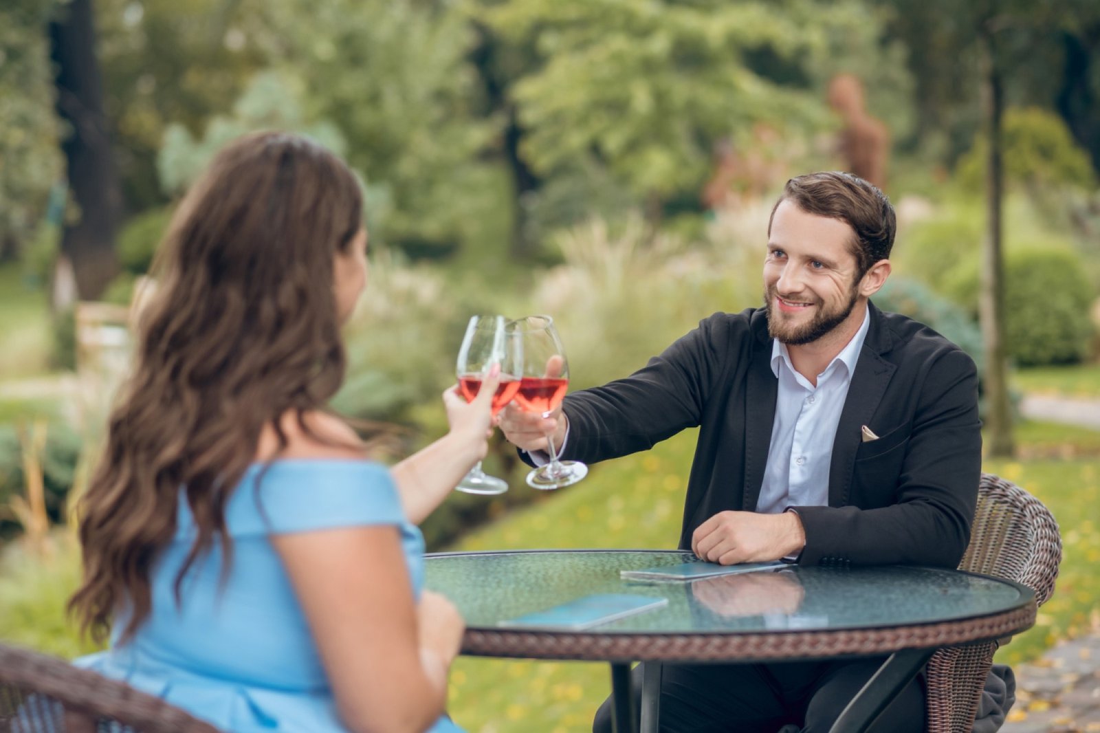 Par på en lugn utomhusdejt som skålar med vin