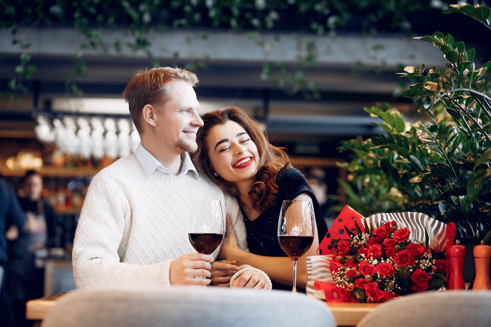 Ett leende par på restaurang som delar en middag och ett glas vin